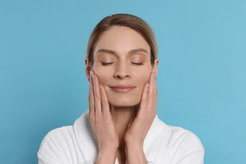 Woman massaging her face on turquoise background