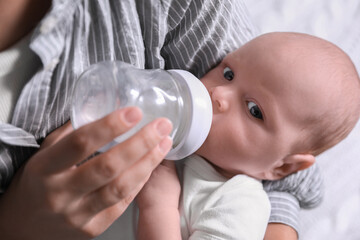 Mother feeding her little baby from bottle, closeup