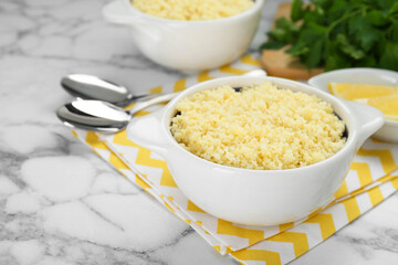 Bowl of tasty couscous on white marble table, closeup. Space for text