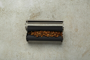 Roller with tobacco on light grey table, top view. Making hand rolled cigarettes