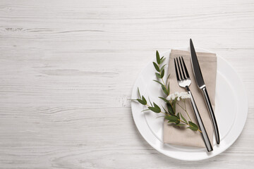 Stylish setting with cutlery and eucalyptus leaves on white wooden table, flat lay. Space for text - obrazy, fototapety, plakaty
