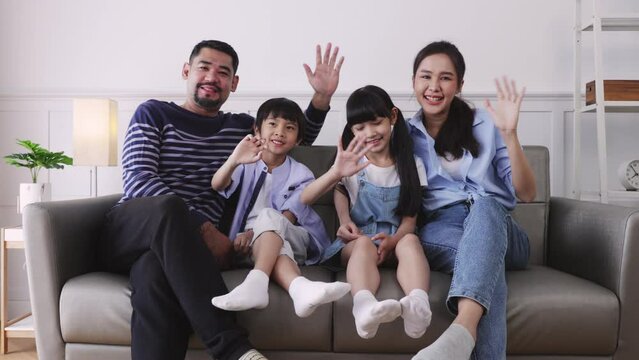 Happy asian family is smiling at the camera.Smiling and waving hello goodbye greetings posing in cozy living room
