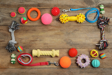 Flat lay composition with dog leashes and toys on wooden background, space for text