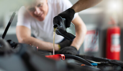 Fototapeta na wymiar Pouring oil to car engine. Closue up male mechanic hand working and service in Car Service station