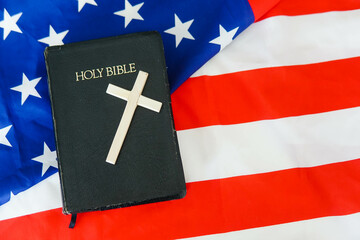 Old Holy Bible with a cross on american flag. Copy space.