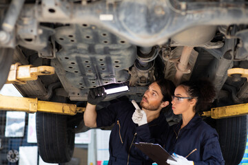 Hispanic Female trainee Mechanics Working Underneath Car Together Car maintenance and auto service garage. Car maintenance and auto service garage concept.