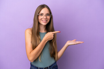Young Lithuanian woman isolated on purple background holding copyspace imaginary on the palm to insert an ad