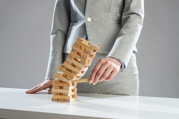 Businesswoman removing wooden block from tower - 582646897