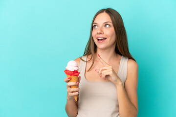 Young Lithuanian woman with cornet ice cream isolated on blue background intending to realizes the...