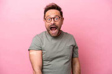 Middle age man wearing a band aids isolated on pink background with surprise and shocked facial...