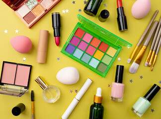 Bright summer eyeshadow palette and makeup products on green background