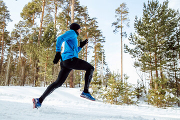 man runner run winter forest in cold weather, side view, cross-country running