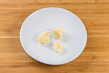 Pieces of the cocoa butter on saucer on wooden surface