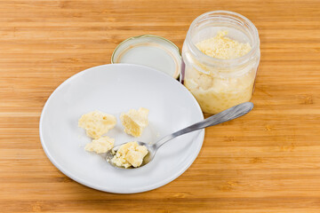 Cocoa butter on saucer and in jar on wooden surface