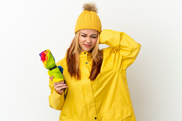 Teenager blonde girl wearing a rainproof coat over isolated white background frustrated and...
