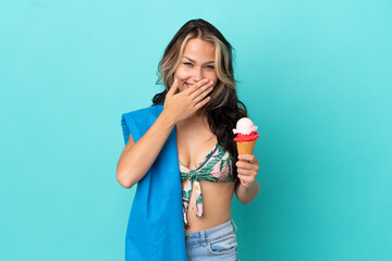 Teenager caucasian girl holding ice cream and towel isolated on blue background happy and smiling covering mouth with hand