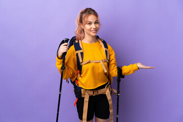 Teenager girl with backpack and trekking poles over isolated purple background extending hands to...