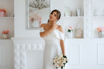Fototapeta na wymiar brunette bride in a tight wedding dress in a bright studio