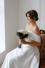 brunette bride in a tight wedding dress in a bright studio