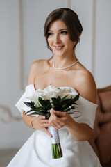 Obraz na płótnie Canvas brunette bride in a tight wedding dress in a bright studio
