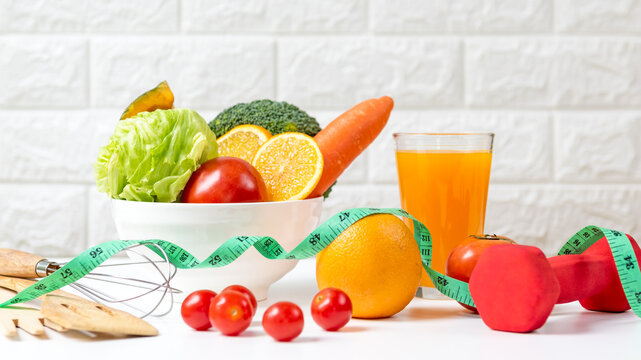 Diet and healthy fresh vegetable fruits for detox body slim fit for health lifestyle with Sport exercise equipment workout and orange juice,  white background. Weight Loss and Diet Concept
