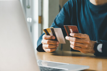 Man hand holding credit card and using laptop at home, Businessman or entrepreneur working, Online shopping, e-commerce, internet banking, spending money concept.