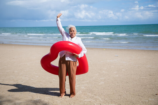 Portrait one mature elderly asian women enjoying summer beach vacations. Bright swimming inflatable ring - Powered by Adobe