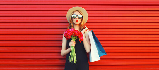 Portrait of beautiful happy young woman with shopping bags and bouquet of flowers wearing summer...