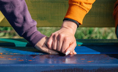 clasped hands of women on rainbow bench