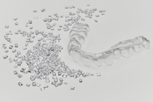plastic teeth retainer bracket with it's plastic resin granulate on white