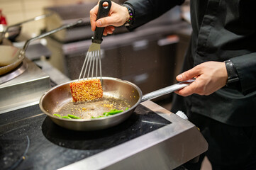 man chef cooking fried tuna fish and green bean in frying pan on kitchen