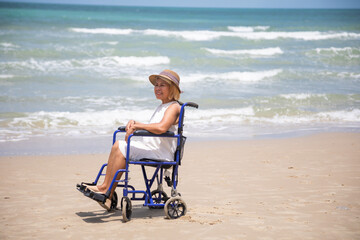 elderly asian woman sitting on wheelchair enjoying  relax time on summer beach