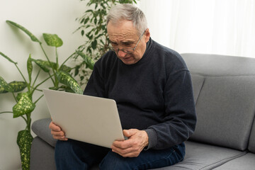 Handsome mature man in casual sitting in home office and working at laptop