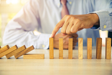 Close-up hand prevent wooden block not falling domino concepts of financial risk management and...