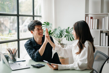 Obraz premium Young Asian business team creative businesspeople coworker, teamwork celebrating achievement and in planning design in creative in office.