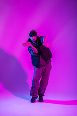 Cool fashion stylish professional male dancer in trendy black clothes dancing in a creative studio with pink and neon lights