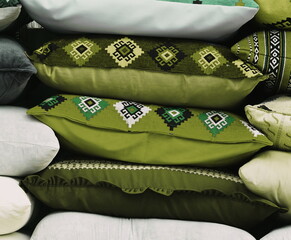 A stack of green pillows with an ornament. Handmade pillow sale on the street