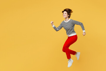 Fototapeta na wymiar Full body side view sporty happy fun young woman wearing casual black and white shirt jump high run fast hurrying in rush isolated on plain yellow color background studio portrait. Lifestyle concept.
