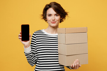 Young woman wearing casual striped shirt holding in hand stack cardboard blank boxes use mobile...
