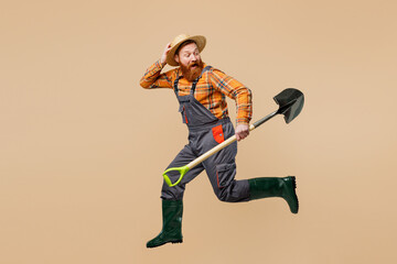 Full body young bearded man wears straw hat overalls gumboots work in garden run hurrying look...