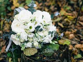 Closeup bride's wedding bouquet of pink roses on natural background on tree stump in forest
