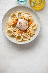 Plate with catalan escudella on a light-beige stone background, vertical shot, copy space, above view
