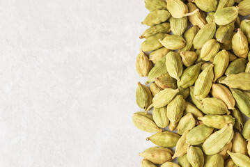 Green cardamom pods on light background with copy space.  Natural texture of traditional Indian condiment