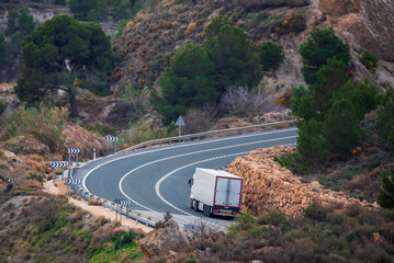 Truck with a refrigerated semi-trailer driving on a two-way road, with two uphill lanes, one for...