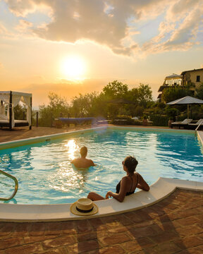 Luxury country house with swimming pool in Italy. Pool and old farmhouse during sunset in central Italy. Couple on Vacation at a luxury villa in Italy, men and woman watching the sunset. 