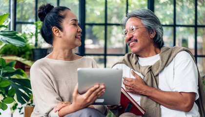 Senior couple asian family having good time using tablet computer together.Happy elderly husband and wife checking social media and reading news or shopping online while sitting at home