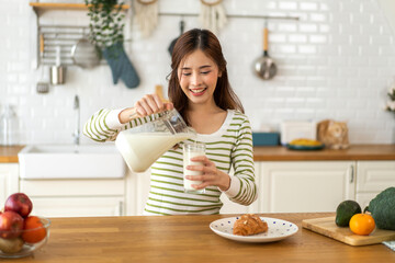 Portrait of beauty healthy asian woman smiling and having protein breakfast drinking and hold glasses of milk on counter in kitchen at home.Diet concept.healthy drink