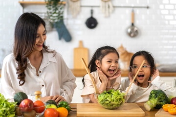Portrait of enjoy happy love asian family mother with little asian girl daughter child having fun help cooking food healthy eat together with fresh vegetable salad  ingredient in kitchen