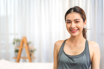 Portrait smiling happy sport asian beauty body slim woman in sportswear sitting relax and practicing yoga and do fitness exercise pose in bedroom at home.Diet concept.Fitness and healthy