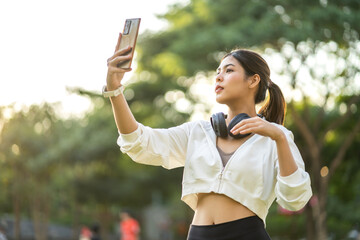 Portrait of smiling cheerful beautiful pretty asian woman clean fresh healthy white skin posing smile look at camera making live selfie on smartphone at green park